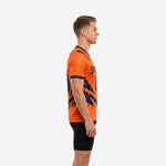 Custom orange and navy soccer training jersey showing side panel geometric design and navy sleeve cuff trim, left side view