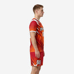 Custom orange and red soccer uniform side view showing sublimated spike design on jersey and shorts