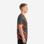 Custom orange soccer jersey side profile view showing diagonal slash-stripe pattern running from shoulder to hem in Charcoal and orange