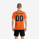 Close detail of custom orange soccer jersey with sublimated black geometric grid pattern and white collar trim