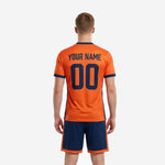 Custom orange soccer jersey detail showing navy blue V-neck collar, sleeve cuffs, and sublimated team name