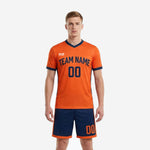 Custom orange soccer uniform with navy blue contrast panels, men's full kit front view showing team name and number