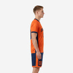 Men's orange soccer uniform side view showing navy blue side panel construction on jersey and shorts
