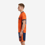 Orange and navy blue soccer uniform set side view showing contrast hem band and shorts panel detail
