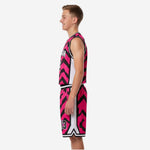 Side view of custom pink and black youth basketball uniform showing white contrast side panel on jersey, armhole binding detail, and matching chevron shorts with drawcord waistband