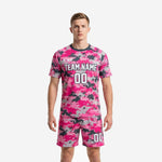 Custom pink digital camo soccer uniforms front view showing hot pink and charcoal 2-piece kit with team name and number print on male model