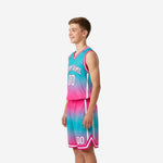 Side view of custom teal and pink youth basketball uniform set showing armhole binding and matching gradient shorts with white trim
