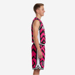 Custom pink youth basketball uniforms front view showing V-neckline stripe binding, team name across chest, and player number 13 on hot pink and black chevron jersey with matching shorts