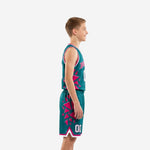 Front view of custom pink and teal youth basketball uniform set with arced team name on chest, white front number, and matching sublimated shorts