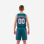 Side view of teal and pink youth basketball uniform showing geometric triangle side-panel pattern running from jersey ribs through the shorts legs