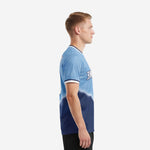 Custom blue and white soccer jersey left side view displaying Powder Blue to Navy Blue gradient and white sleeve cuff trim on male model