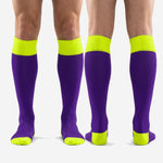 Full length pair of custom purple and gold soccer socks laid flat showing colorblock construction