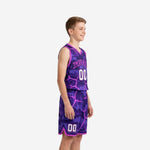 Front view of custom purple youth basketball uniform set with pink camo fracture overlay, arced team name in pink collegiate lettering, and white front number