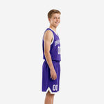 Side view of custom purple youth basketball uniform showing white armhole binding, solid purple jersey body, and purple shorts with white V-notch hem accent