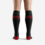 Close-up of custom red and black soccer socks showing double red stripe placement below ribbed cuff