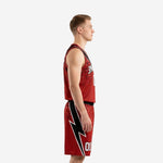 Side view of custom red and black basketball uniform set showing bolt graphic on shorts leg panel and V-neck jersey armhole binding
