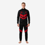 Custom red and black soccer tracksuit front view showing chevron panels and team name print on jet black jacket and tapered pants