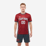 Custom red and black soccer uniforms front view showing crimson jersey with charcoal side panels and matching shorts on male model