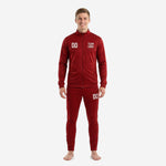 Custom red soccer tracksuit front view showing crimson full-zip jacket with team logo and number print and matching tapered pants on male model