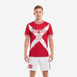 Custom red soccer uniform with white brush-stroke X print on jersey and white shorts with red side stripe, front view on male model