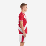 Sublimated red soccer uniform showing white brush-stroke panel detail on jersey side and red stripe on white shorts, left side view