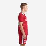 Custom red soccer uniform left side view showing white shoulder panel and shorts side stripe on adult male model