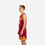 Youth boy wearing custom red youth basketball uniforms with gold V-neck binding, arced team name across chest, and number 00 below in gold with white outline