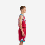 Front view of custom red youth basketball uniforms with teal V-neck binding, arched team name across chest, and number 00 on jersey and shorts