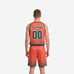 Side view of orange reverse side reversible basketball uniform showing contrast teal waistband trim and halftone dot pattern on shorts hem