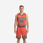 Reverse side of custom reversible team basketball uniforms showing orange dominant jersey and shorts with teal team name, number, and halftone dot hem pattern