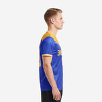 Custom Royal Blue soccer jersey with Athletic Gold shoulder yoke and white accent stripe, left side view on male model