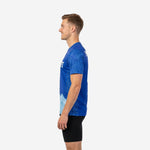 Royal blue soccer practice jersey with tonal leaf pattern on sleeves and ice blue mountain-scape hem, right side profile