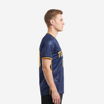 Custom royal blue soccer jersey showing Athletic Gold side panel and sleeve cuff trim on adult male model left side view