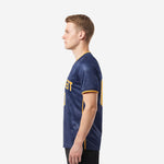 Custom royal blue soccer jersey with tonal geometric chevron sublimation and gold vertical side panels on adult male model right side view