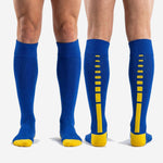 Full length custom royal blue and gold soccer socks over the calf fit shown on standing male model