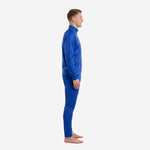Royal blue soccer tracksuit side view on male model showing tapered pants and full-zip jacket with tone-on-tone crest pattern