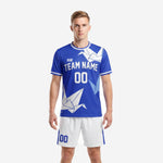 Custom Royal Blue soccer uniform front view showing origami crane geometric print on jersey and white shorts with blue panels