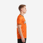 Custom soccer tops orange and white side view left showing sleeve cuff black contrast stripe and athletic cut fit