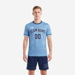 Custom soccer uniform kits for teams in powder blue and navy blue, front view showing sublimated grid pattern jersey and matching shorts on adult male model