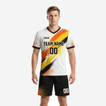 Men's custom soccer uniforms for teams package in white with orange and black brush-stroke print, front view showing team name and number placement