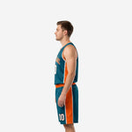 Side view of teal basketball uniform showing wide orange side panel running from jersey armhole down through the shorts leg on adult male model
