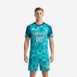 Custom teal hex-print soccer uniform kits for men, front view showing team name and number on jersey with matching shorts