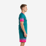 Custom teal and hot pink soccer kit side view showing gradient sleeve fade and matching shorts hem on adult male model