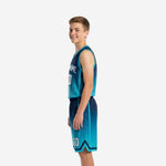 Side view of teal and navy youth basketball uniform set showing hexagonal dot sublimation pattern on jersey and shorts with navy hem band
