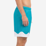 Custom teal soccer shorts showing white wave hem panel and elastic drawcord waistband, left side view on male model