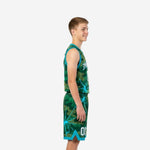Side view of custom teal youth basketball uniforms showing green camo pattern with teal lightning overlay and teal armhole binding