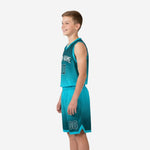 Side view of teal youth basketball uniform showing bound armhole trim, relaxed athletic cut jersey, and matching gradient shorts with teal hem binding