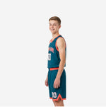 Side view of teal youth basketball uniform showing coral-orange armhole binding curved sweep panel and shorts chevron vent detail at hem