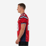 Right side view of red and navy sublimated football jersey showing short sleeve cut with navy and white stripe cuff detail