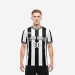 Custom team soccer jersey in black and white vertical stripes with arched team name and front number, front view on male model